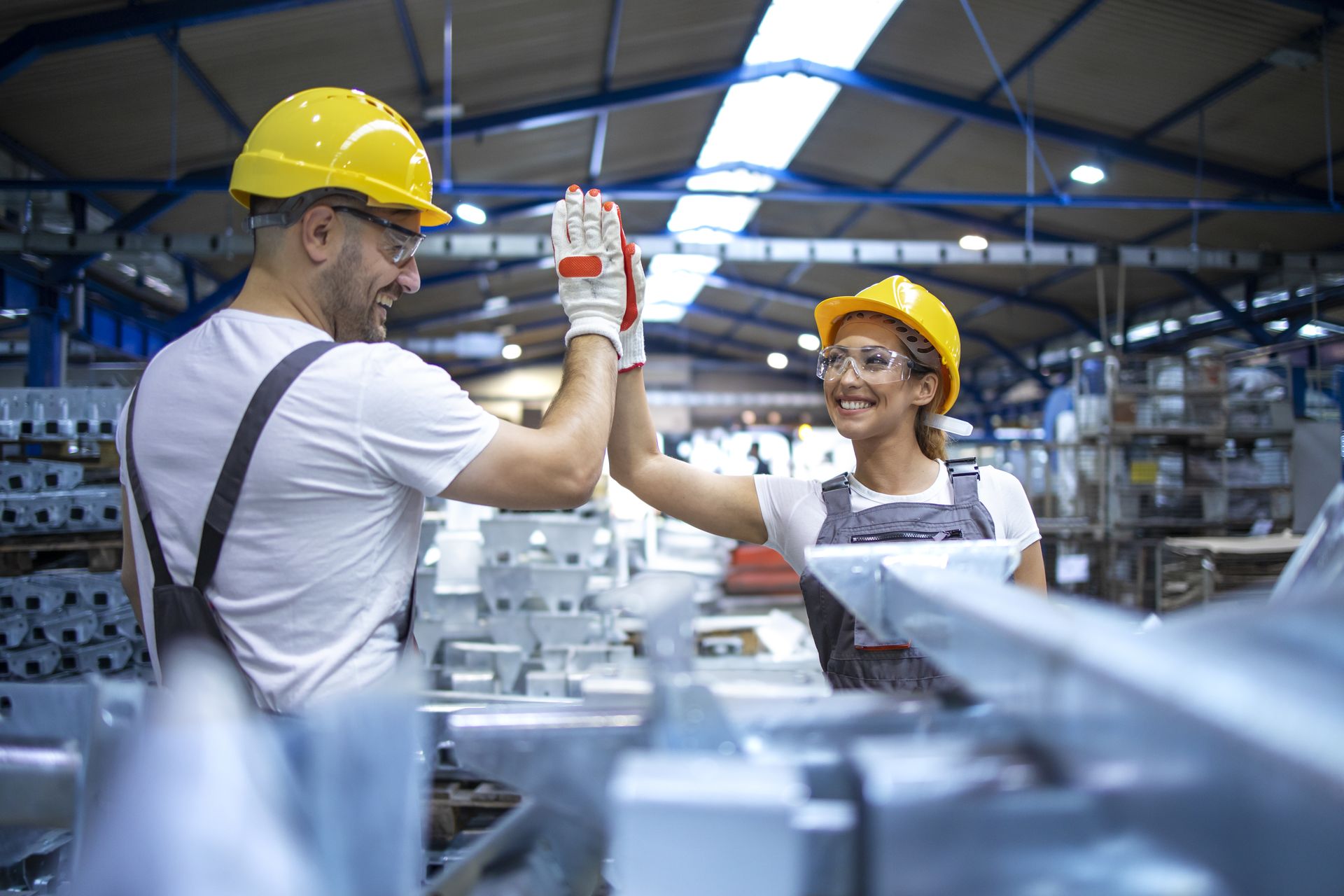 Smiling factory employees giving a high five in a manufacturing plant